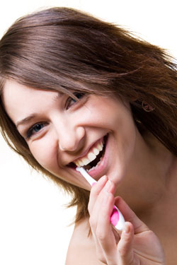 smiling young woman brushing her teeth